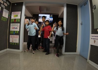 Several children throwing paper planes towards the viewer, down a corridor